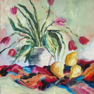 Still life painting of pink and red tulips in a white vase set on colorful fabric. There are three golden yellow pairs next to the right side of the vase.